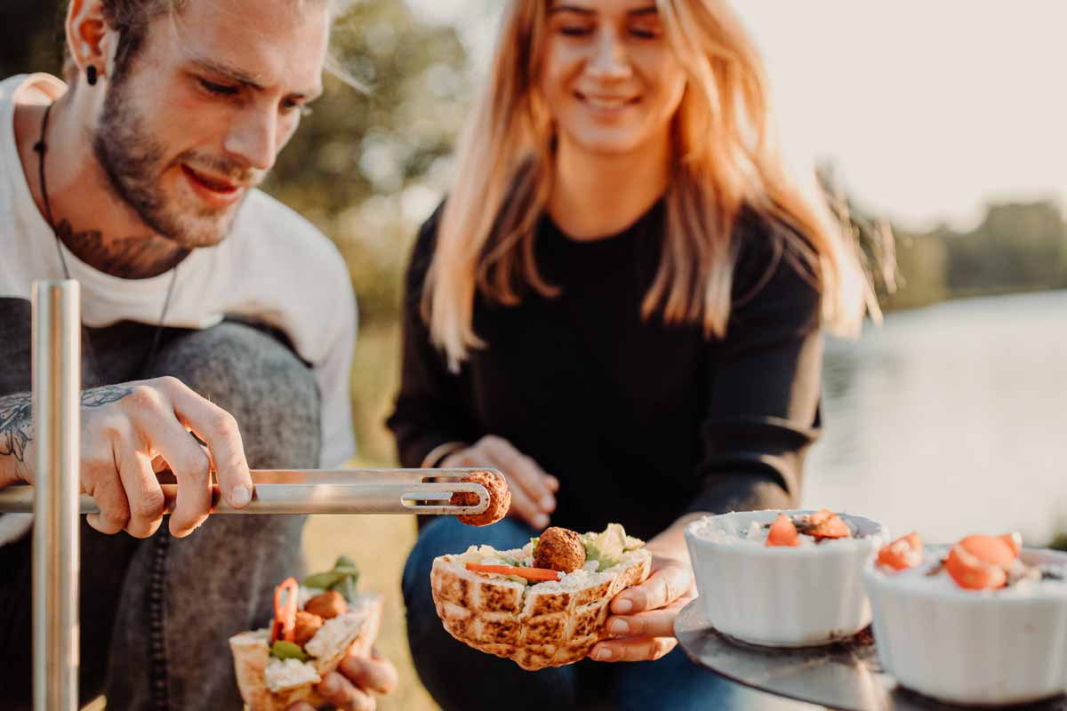 This image shows a man and woman eating food on a picnic table