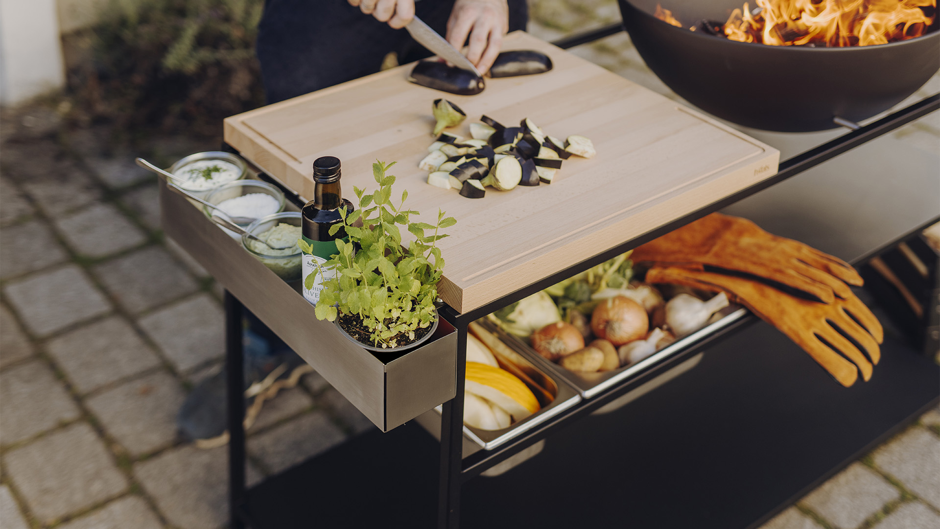 The 00830 Fire Kitchen Tool Box 1 Pdp is shown as a person is cooking food on a grill, creating a stylish and accessible visual.