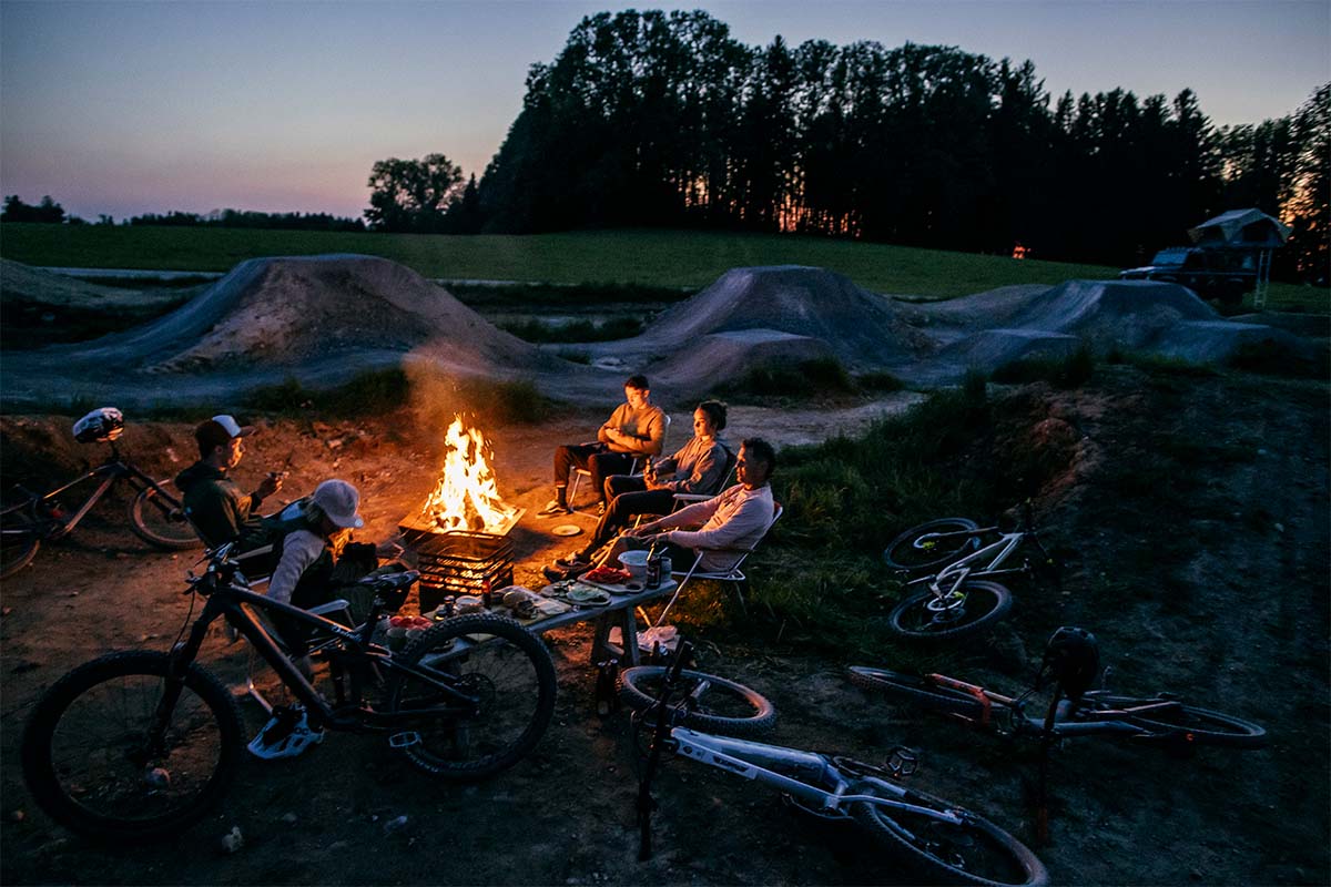 A group of people sitting around a fire the Triple 90 Fireplace complements the moment with its thoughtful design.