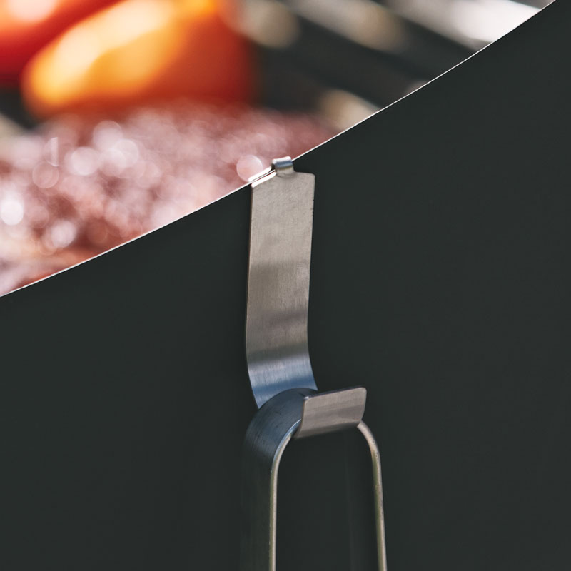 A close up of a metal hook holding a tong and some food, with the Cone h ook adding a functional and elegant touch to the scene.