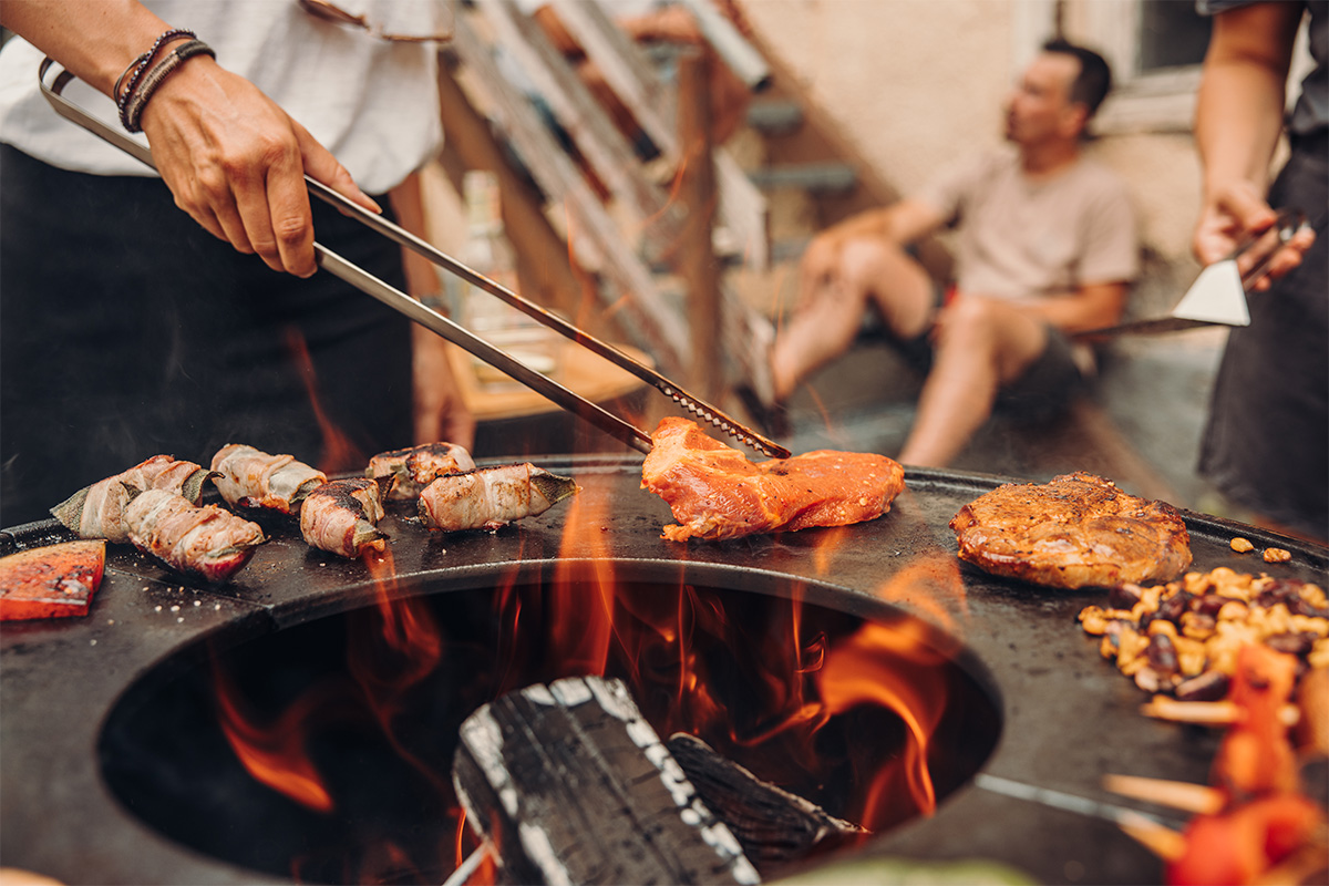 Fire Tongs Illustrated is a person is cooking food on a grill, with the Fire Tongs.