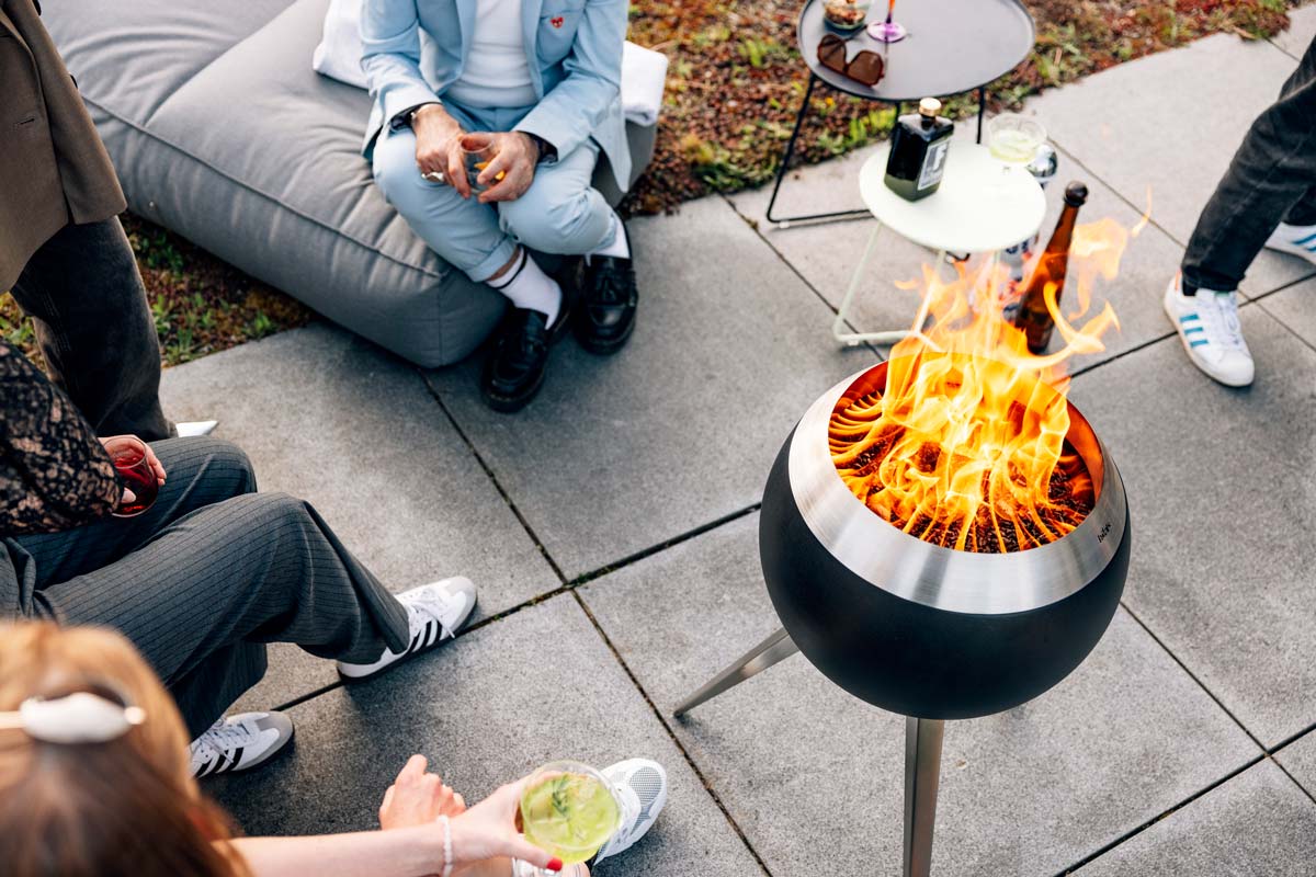 A group of people sitting around a fire pit, with the 00717 Moon 45 with high stand adding a functional and elegant touch to the scene.