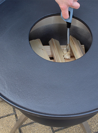 Scene showing a person lighting up a piece of wood in a fire pit