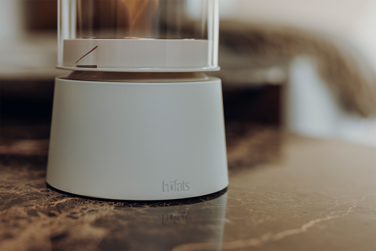 SPIN air 900 Tabletop Fireplace cream SPIN air 1200 creme steht auf einem braunen Tisch ein Foto nur der der Base im Detail