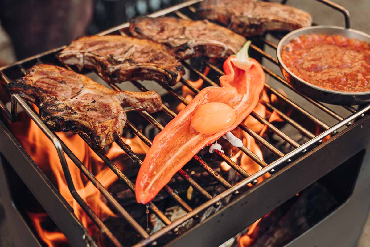 The Beer Box Firebasket is shown as a grill with meat and vegetables on it, creating a stylish and accessible visual.