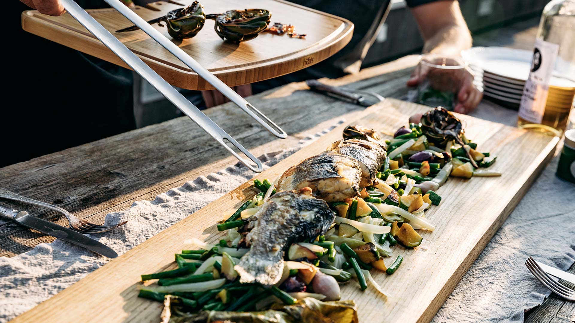 A view of a person cutting a fish on a wooden cutting board