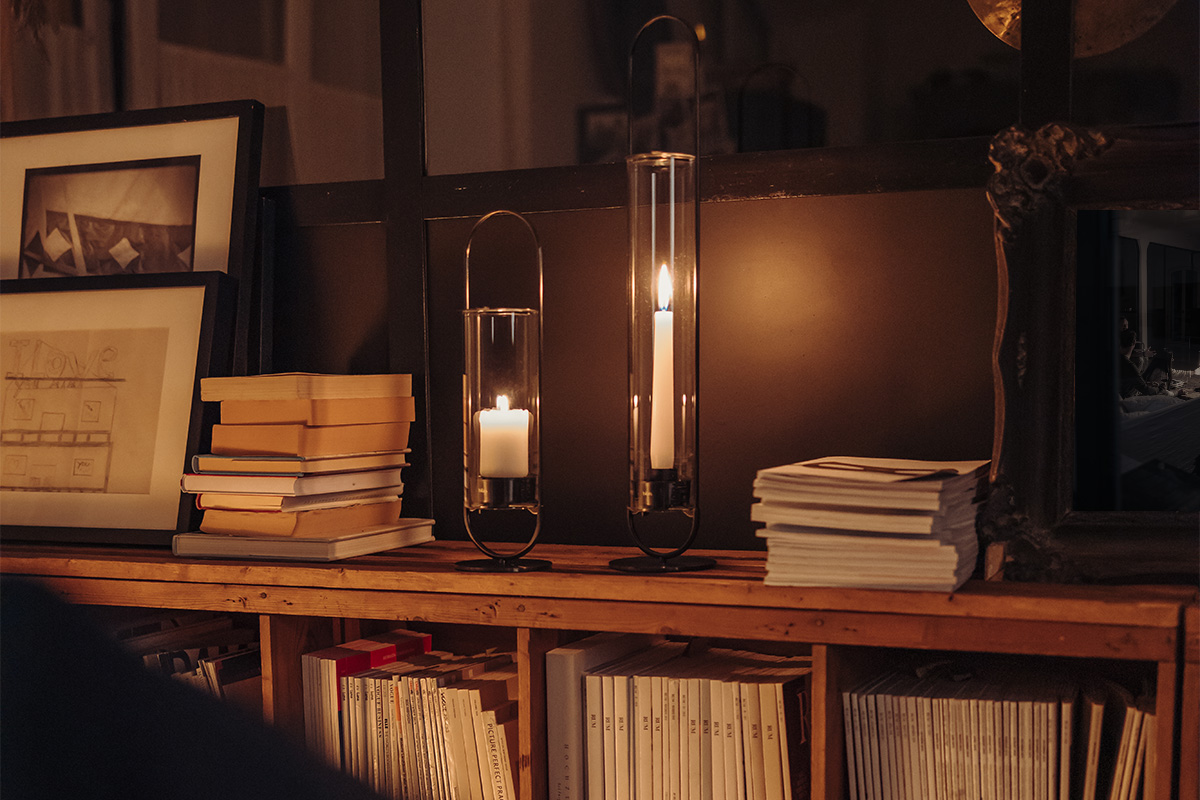 The 00273 Oval Candle 35 black integrates seamlessly into the setting, where a table with a lamp, books and a picture.