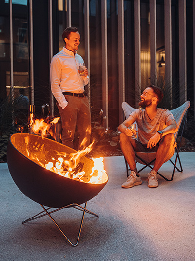 An image showing two men sitting around a fire pit, with the BOWL Fire Bowl.
