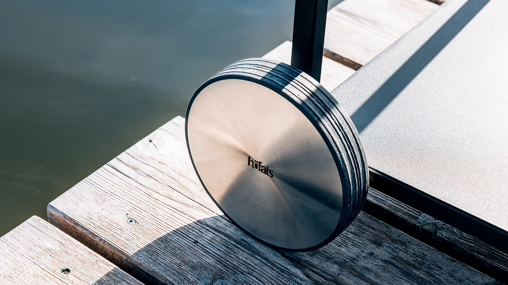 Illustrated is a metal disc on a wooden dock, with the FIRE KITCHEN Wheel Set (2 pcs).