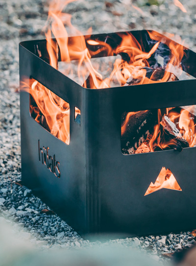 The Beer Box Firebasket integrates seamlessly into the setting, where a fire pit with flames burning in it