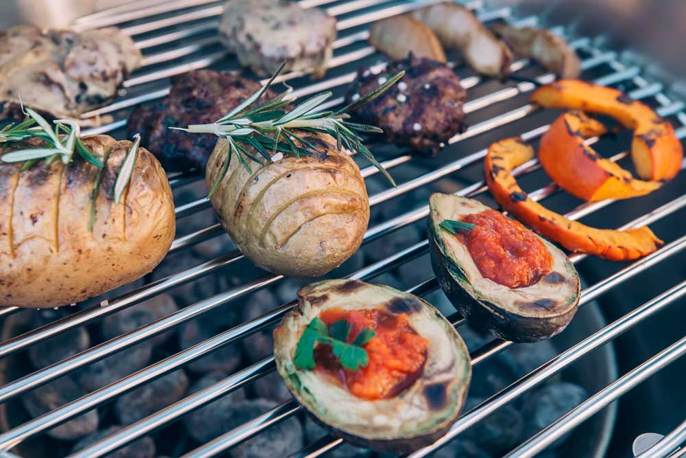 Depicted here is a grill with grilles and vegetables on it, with the CONE Charcoal Grill.