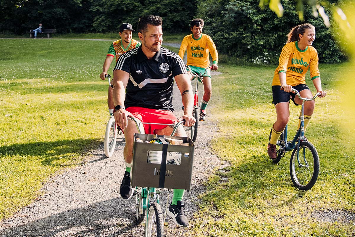 A group of people riding bikes down a dirt road, with the Beer Box Firebasket adding a functional and elegant touch to the scene.