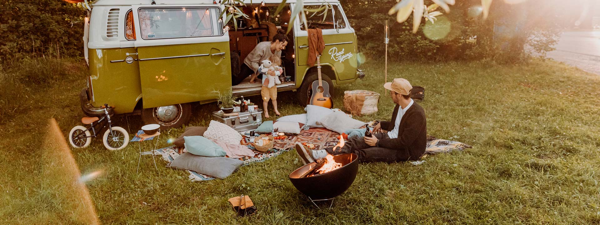 Experience a couple sitting on the grass next to a van with the refined touch of the Bowl Firebowl