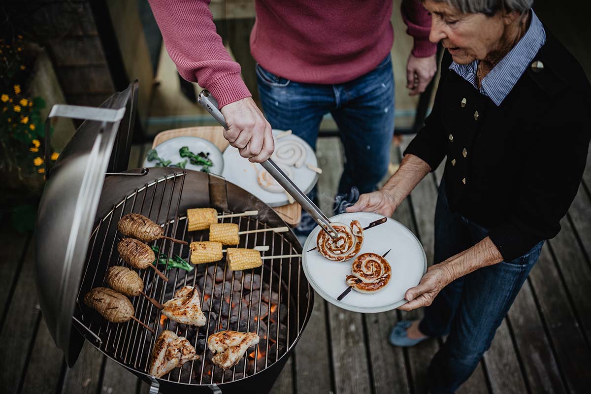 Depicted here is a man and woman grilling food on a grill, with the CONE Charcoal Grill.
