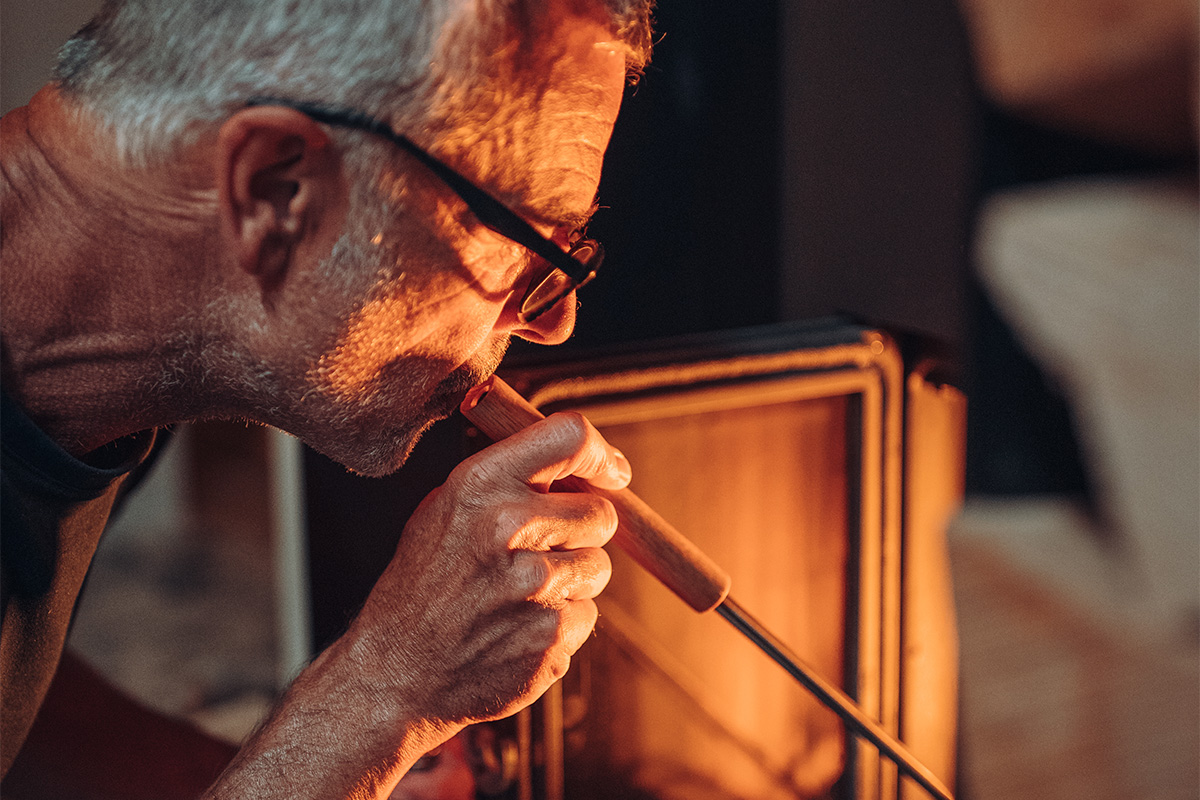 The 00251 Fire Tools Set 3 pcsis shown as a man with glasses is using the blower to start a fire, creating a stylish and accessible visual.