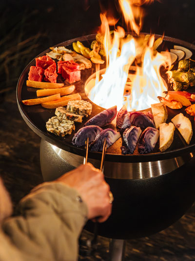 The 00861 Moon 45 Plancha integrates seamlessly into the setting, where a person is grilling food with a tong.