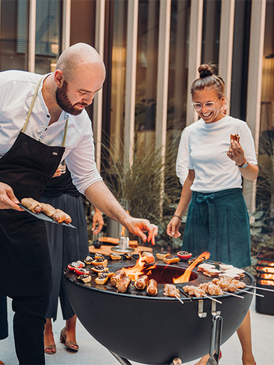 A view of a man and woman grilling, with the BOWL Grid.