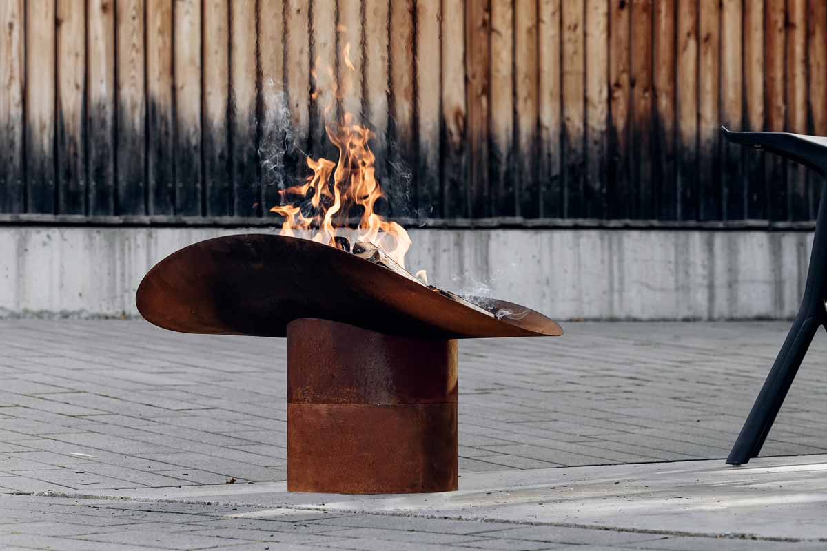 ELLIPSE Foot Depicted here is a fire pit with a chair and a table, with the ELLIPSE Fire Bowl.