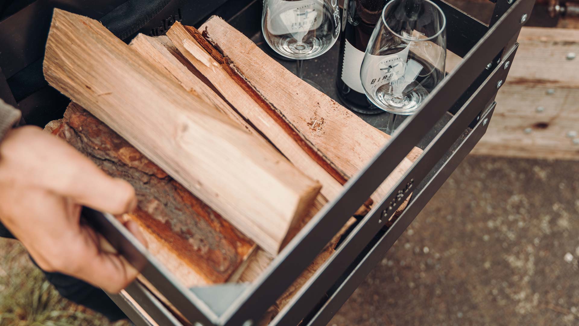 Depicted here is a person holding a tray of wood, with the Premium Firewood.