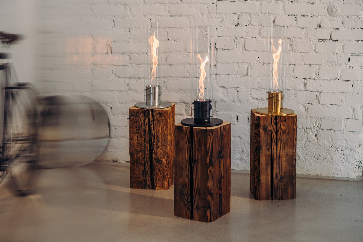 Scene showing a couple of candles sitting on top of a table, where the 00699 Spin 1200 Tablefire Gold stands out for its practical elegance.