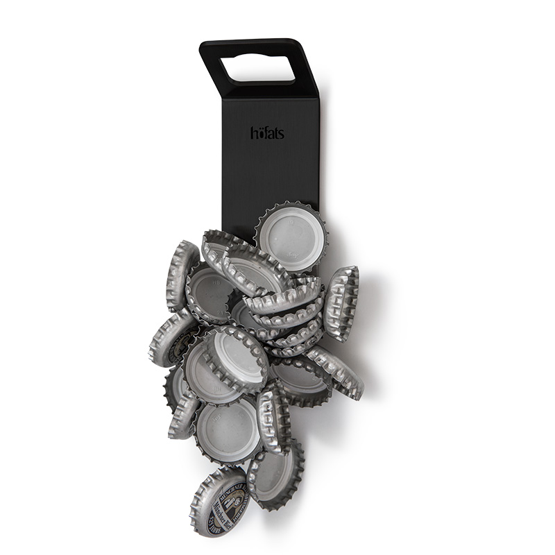 The 00841 Johnny Catch Magnet Black Bottleopener is shown as a bottle opener with bottle caps sticking to it, creating a stylish and accessible visual.