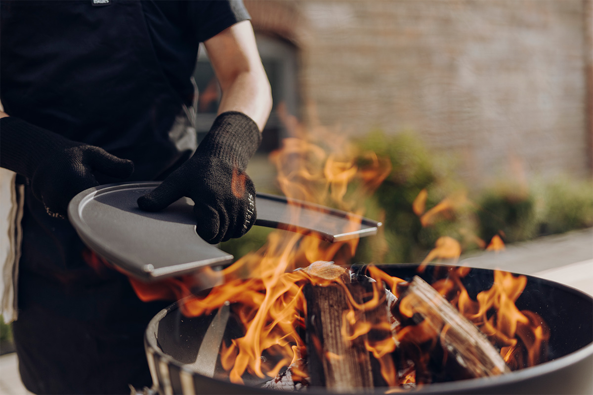 An image showing a person is cooking on a grill with a spat, with the Fire Gloves Aramid.