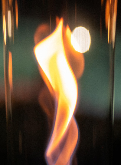 Depicted here is a fire is lit in the dark, with the SPIN 1200 Tabletop Fireplace silver.