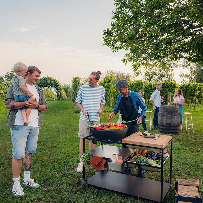 An inviting scene with a group of people standing around a table, highlighted by the presence of the Fire Kitchen