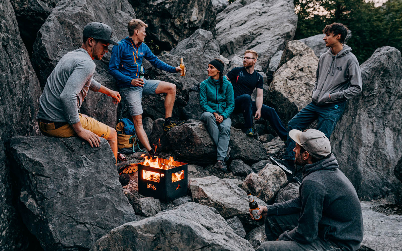 Illustrated is a group of people sitting around a fire, with the BEER BOX Fire Basket.