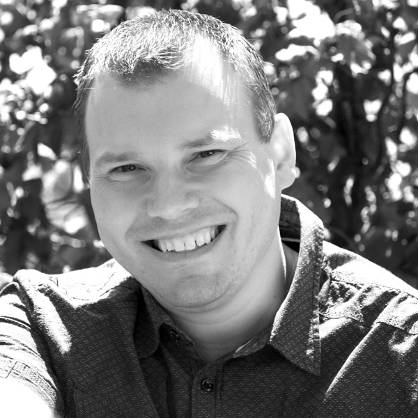 a man smiling while sitting in a park.