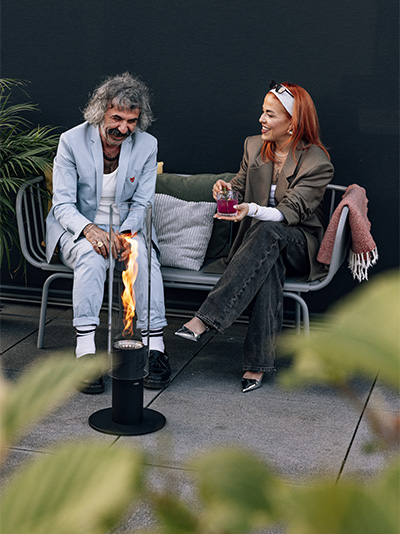 A woman sitting on a bench the Spin 1500 Pedestal Fireplace complements the moment with its thoughtful design.