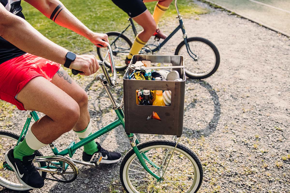 The Beer Box Firebasket is shown as a man riding a bike with the beer box attached to the handlebar, creating a stylish and accessible visual.