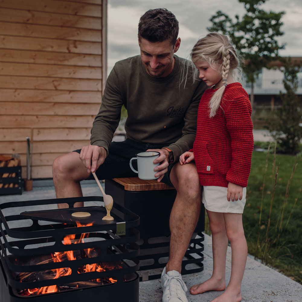 A man and woman sitting by a fire, enriched by the presence of the Hofats Cube