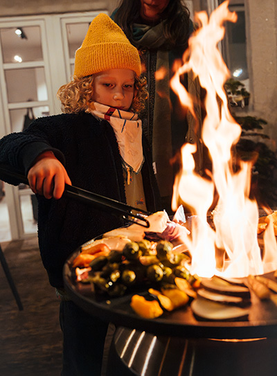 Scene showing a woman and a child grilling on a MOON, where the Moon Plancha stands out for its practical elegance.