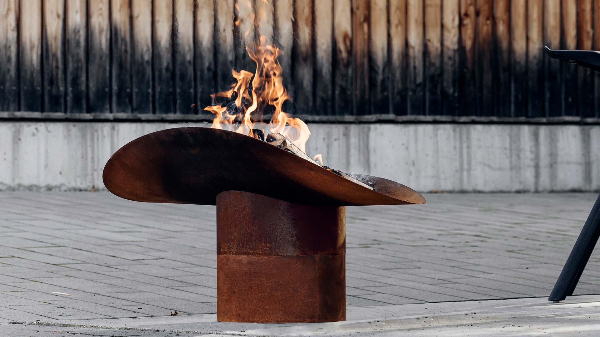 An image showing a fire pit with a fire burning in it, with the ELLIPSE Fire Bowl.