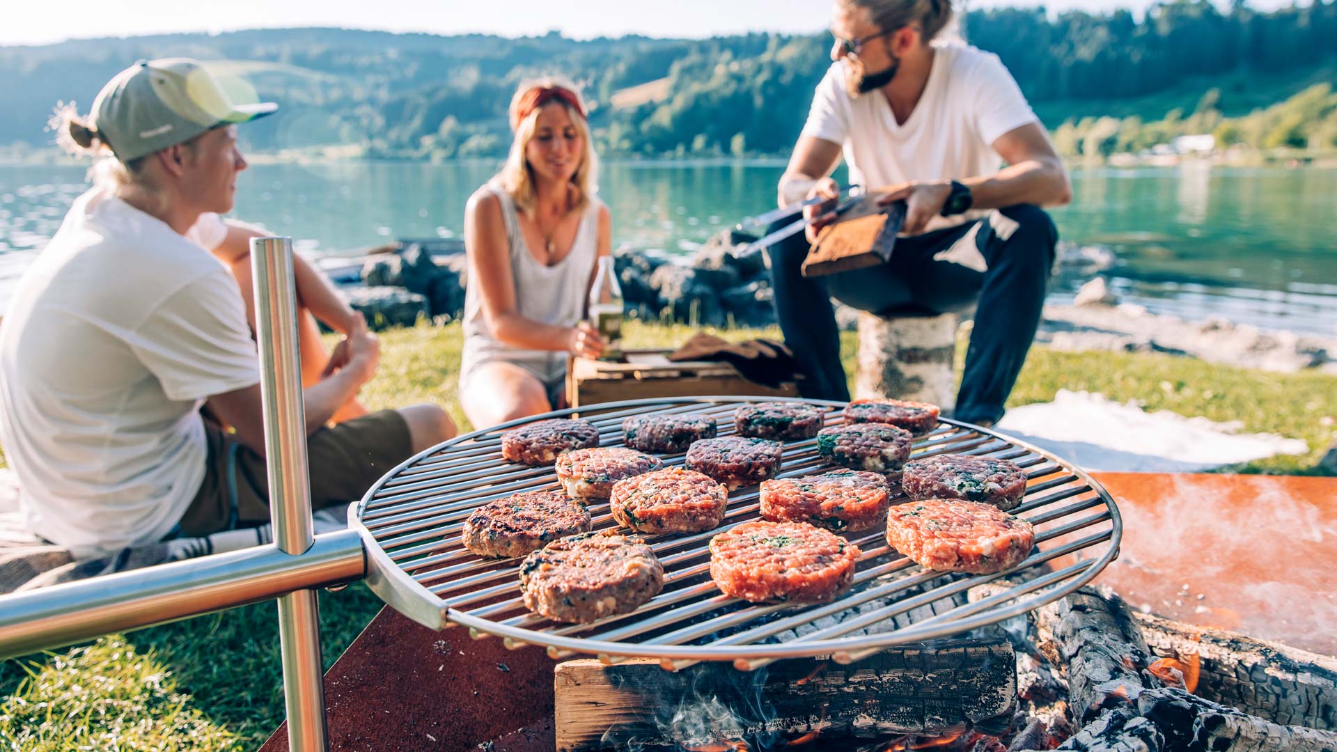 A depiction of a man and woman grilling meat on a grill, featuring the Triple 90 Fireplace BBQ Set as a central and purposeful element.