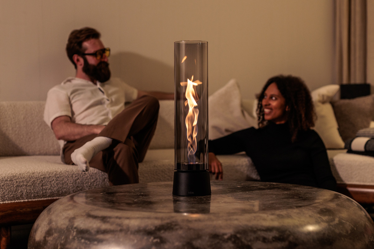 SPIN air 1200 Tabletop Fireplace all black Zwei Personen sitzen auf dre Couch. Im Vordergrund SPIN air 1200 mit Flamme auf Couchtisch.