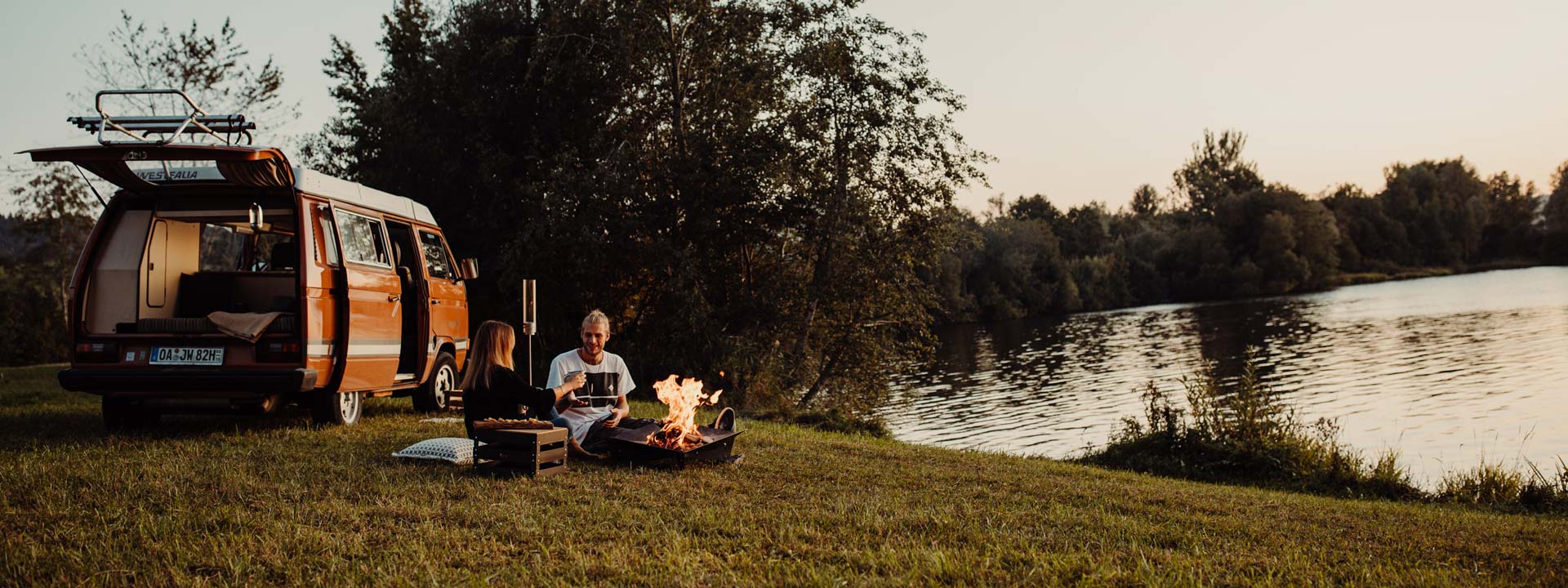 A couple sitting on the grass next to a van the Triple Fireplace complements the moment with its thoughtful design.