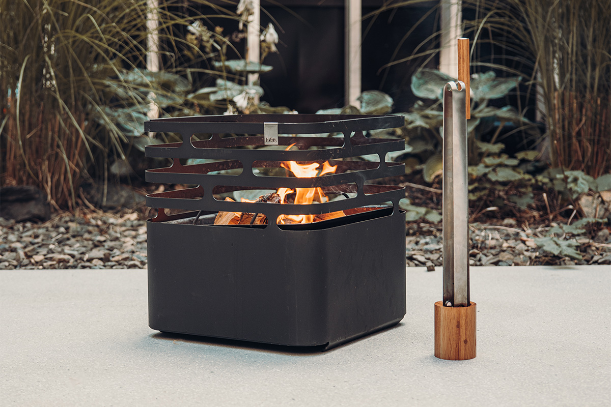 Depicted here is a fire pit with a fire in it, with the Wooden Base for Blow Poker and Fire Tongs.