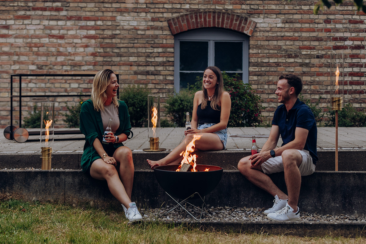 a man and woman sitting on a wall with a fire.