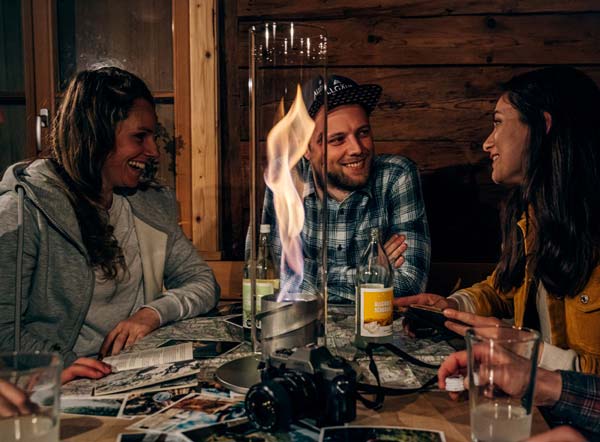 Depicted here is a group of friends sitting around a table at a restaurant, with the SPIN 120 Table Fire silver.