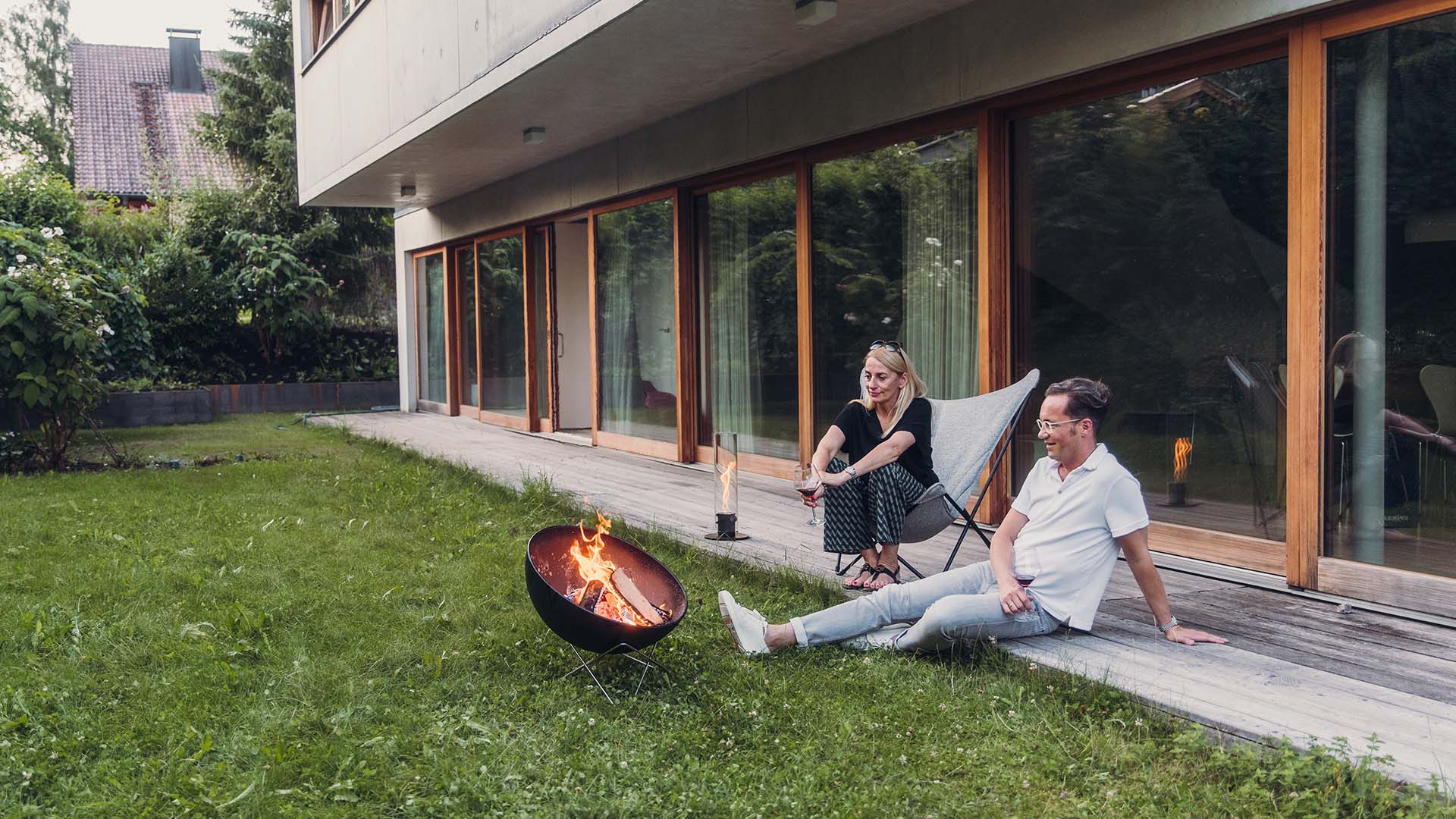 Experience a man and woman sitting on the grass next to a fire with the refined touch of the 00343 Bowl 57 Star Stand