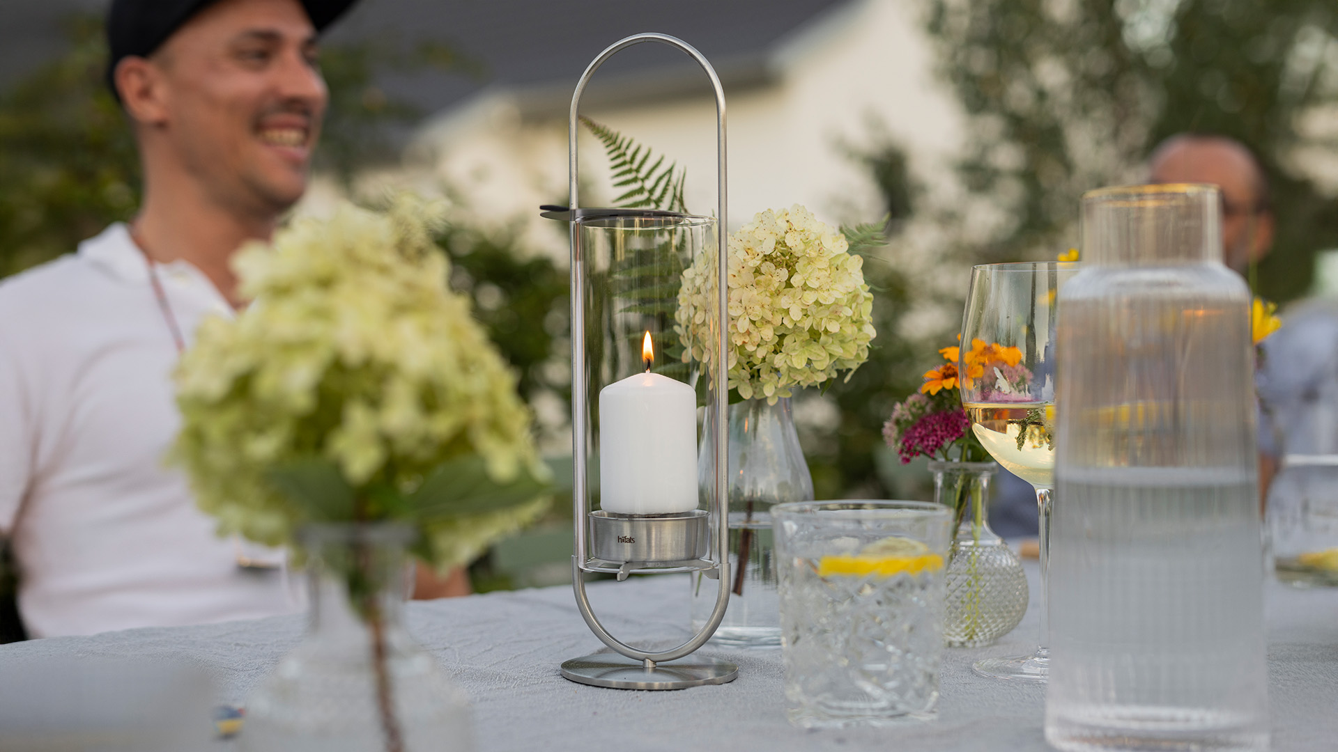 Experience a man sitting at a table with flowers and candles with the refined touch of the 00271 Oval Candle 35