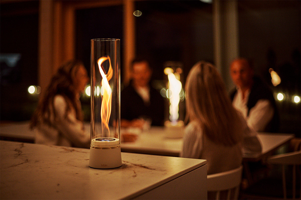 SPIN air 900 Tabletop Fireplace cream Im Fokus SPIN air 900 creme, im Hintergrund vier Personen die sich unterhalten.