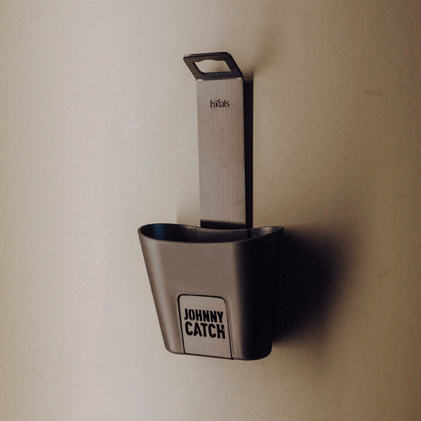 An animated picture showing the 00842 Johnny Catch Cup Black Bottleopener in action. A man opening a bottle of orange juice