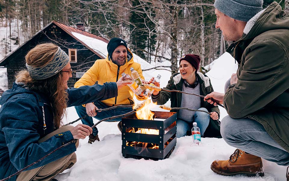 Illustrated is a group of people sitting around a campfire, with the Atmospheric image Christmas for Console.