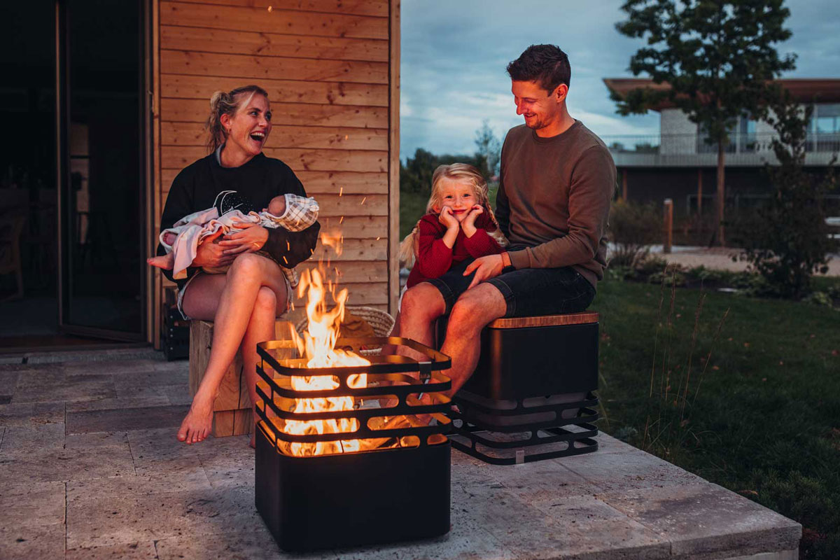 A family sitting around a fire pit the Cube Firebasket black complements the moment with its thoughtful design.