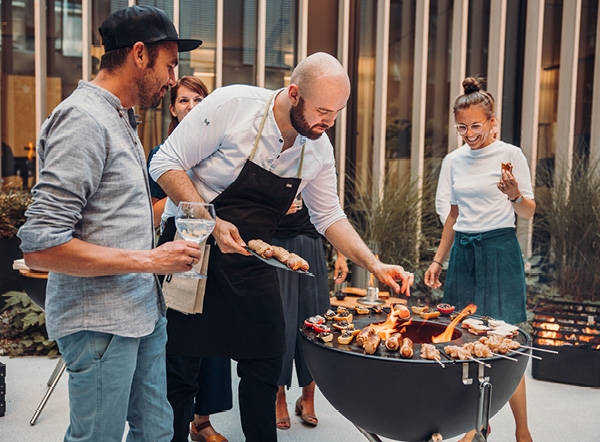 Grilling on the plancha over the fire An image showing a man wearing a black apron, with the CUBE Plancha.