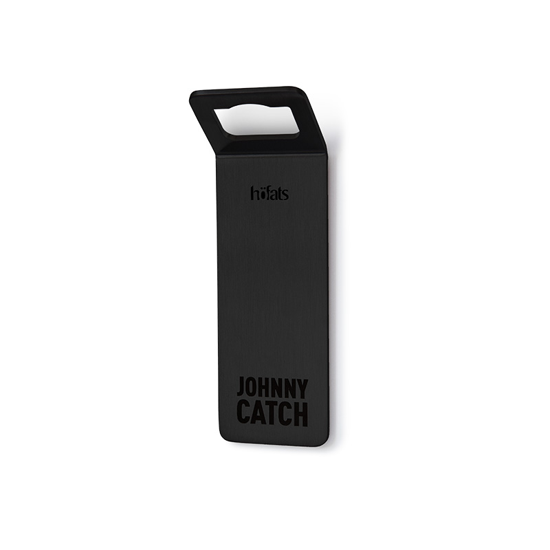 A black steel piece with the words johnny catch on it, enriched by the presence of the 00841 Johnny Catch Magnet Black Bottleopener, which merges design with utility.