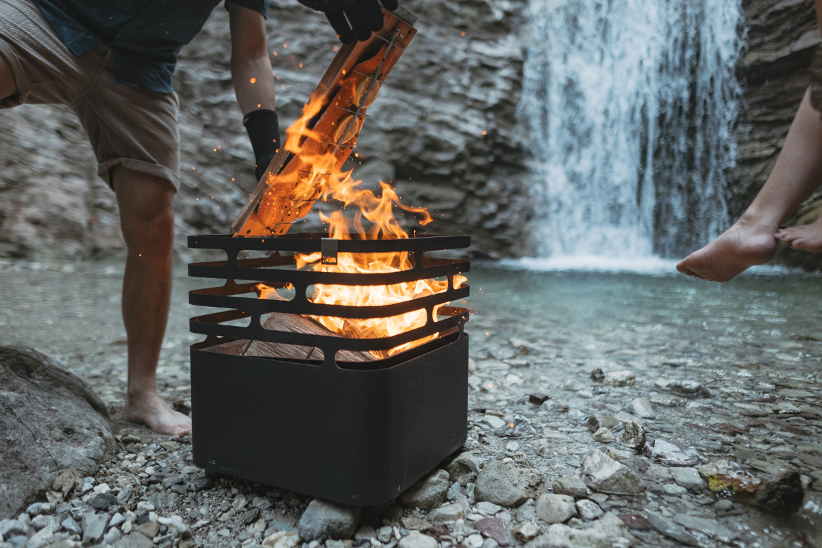 Flame-grilled salmon board A man standing next to a fire in a small box, with the 00702 Flame-grilled salmon board adding a functional and elegant touch to the scene.